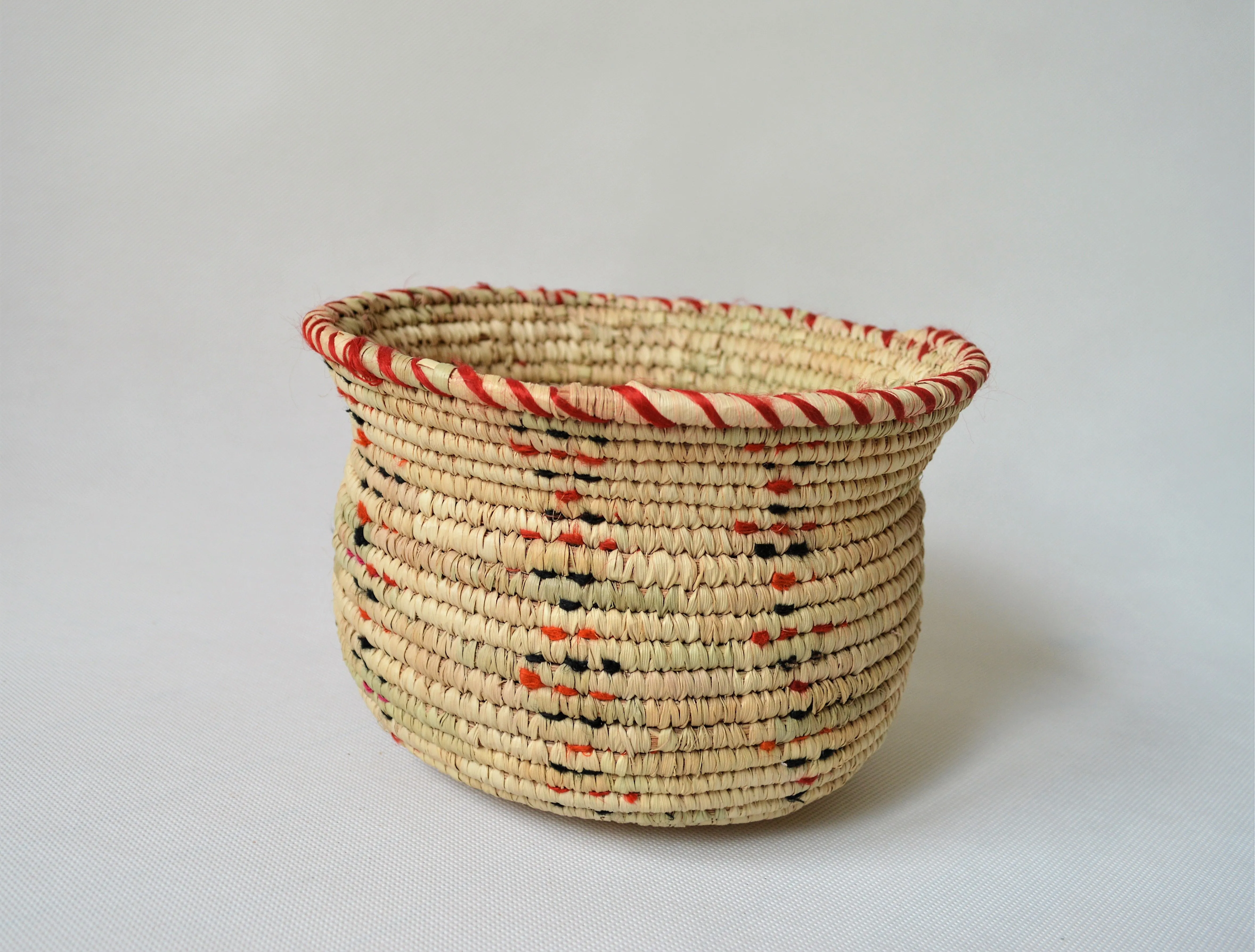 Wide woven bowl decorated with red and black fabric