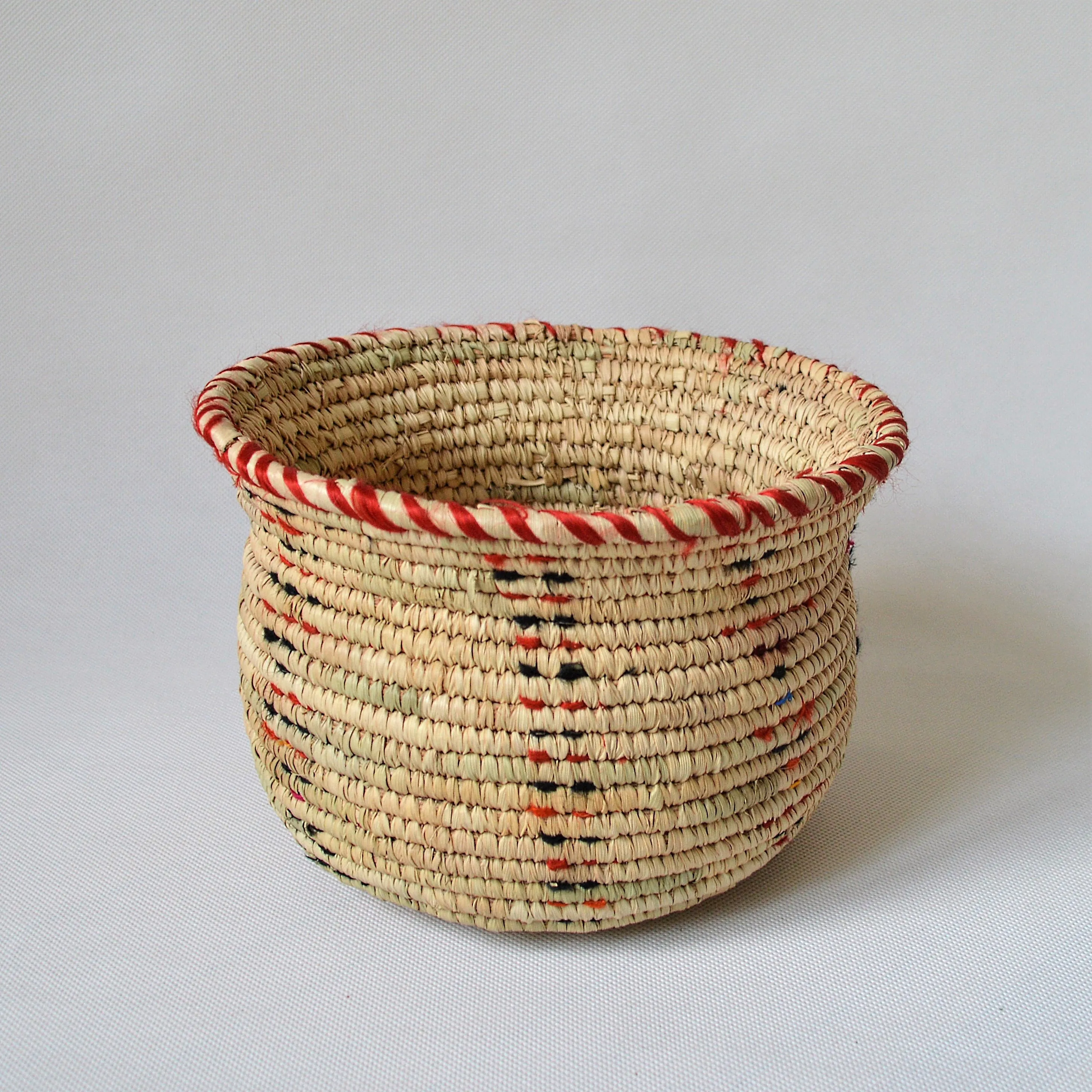 Wide woven bowl decorated with red and black fabric